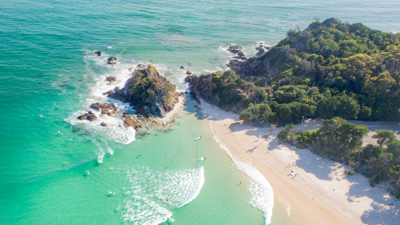 Aerial view of The Pass beach Byron Bay with surfers in turquoise wate